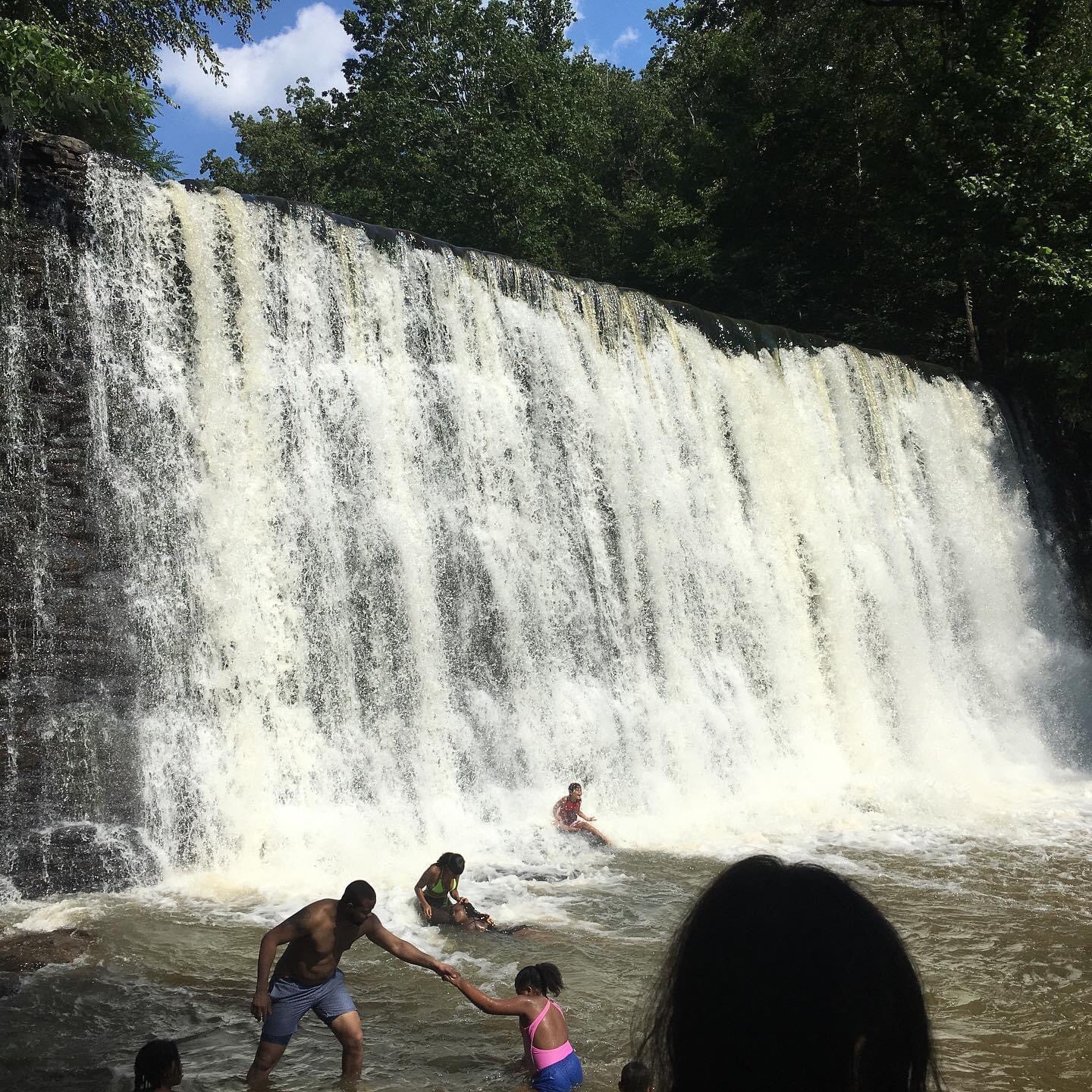 People relaxing at the foot of a waterfall.